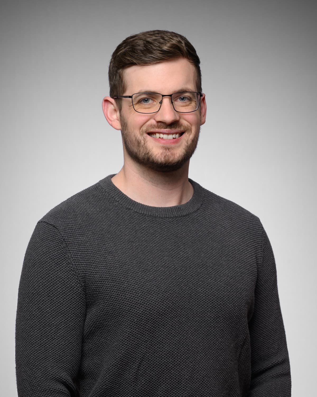 Dennis Spohn, founder of VeteranAI, in a grey sweater against a grey studio backdrop.